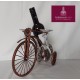 Soporte en forma de bicicleta para botella de vino con copas y rosa.